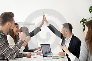 Smiling colleagues giving high five excited by business results