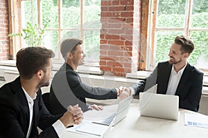 Smiling colleagues greeting each other with handshakes.