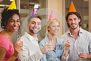 Smiling colleagues holding champagne flute in birthday party