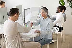 Smiling young woman handshaking satisfied client making deal in