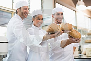 Smiling colleagues showing loaf of bread