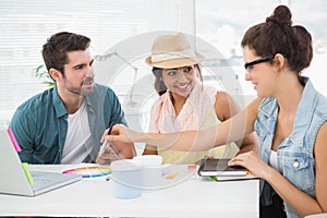 Smiling colleagues speaking together at desk