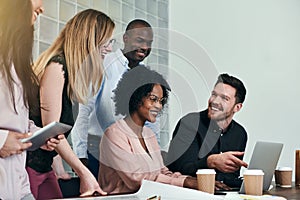 Smiling colleagues working together around a desk in an office