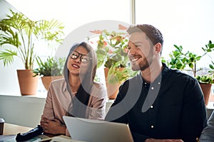 Smiling colleagues working together at a table in an office