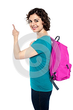 Smiling college student pointing towards the wall