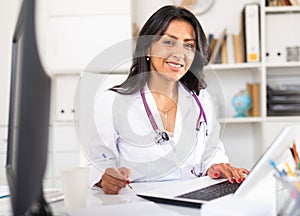 Smiling Colombian woman physician consulting in medical office