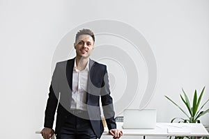 Smiling company CEO posing near office desk