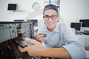 Smiling computer engineer working on broken console with screwdriver