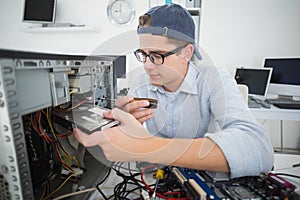 Smiling computer engineer working on broken console with screwdriver