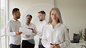 Smiling confident business leader looking at camera and standing in an office at team meeting