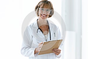 Smiling confident female doctor with eyeglasses looking at camera in the office at hospital.