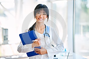 Smiling confident female doctor holding clipboard posing in hospital