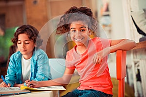 Smiling and confident girl writing her assignment in the class