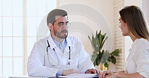 Smiling confident male general practitioner discussing treatment plan with patient.