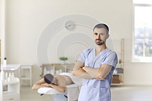 Smiling confident man masseur standing over relaxing man patient