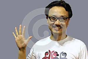 A smiling and confident manipuri north east indian man with spectacles showing the sign of five with fingers photo