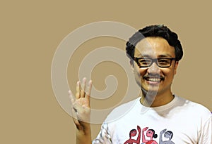 A smiling and confident manipuri north east indian man with spectacles showing the sign of four with fingers photo