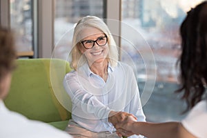 Smiling confident mature woman job seeker applicant handshaking hr