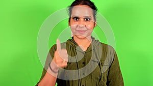 Smiling Confident woman giving thumbs up in front of a green screen wearing a casual green shirt closeup