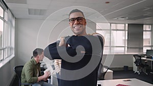 Smiling confident young businessman crossing his arms in front of business team having conversation in office