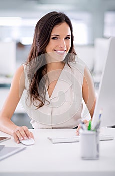 Smiling, confident and young female business worker sitting at a office computer. Portrait of a market research