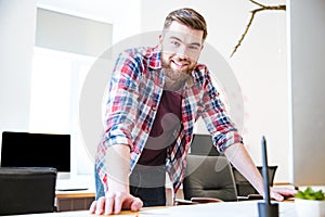 Smiling confident young male with beard standing in office