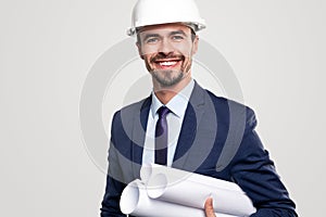 Smiling construction engineer with blueprints looking at camera