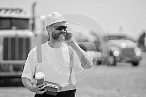 smiling construction site and worker with coffee. caucasian construction manager. Worker with phone at construction site
