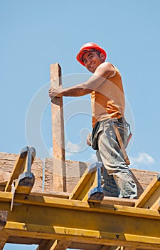 Smiling construction worker with formwork beam