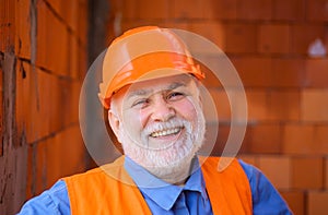 Smiling construction worker in safety vest and hard hat. Bearded engineer, architect builder in protective helmet. House