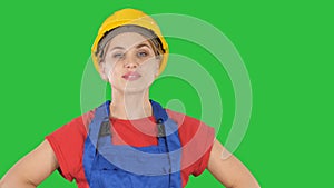 Smiling constructor worker woman standing and changing poses fold hands, hands on hips, hands in pockets on a green