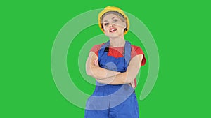 Smiling constructor worker woman standing and changing poses Fold hands, hands on hips, hands in pockets on a Green