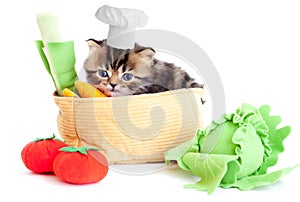 Smiling cook kitten with toy vegetables isolated
