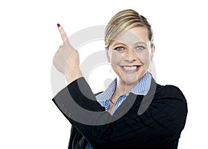 Smiling corporate woman pointing upwards