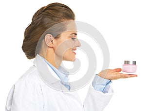 Smiling cosmetologist doctor woman presenting bottle of creme