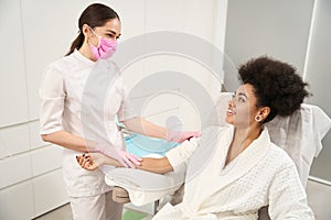 Smiling cosmetologist talking with lady before procedure