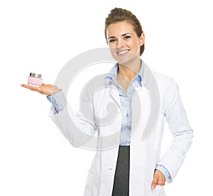 Smiling cosmetologist woman showing cream bottle