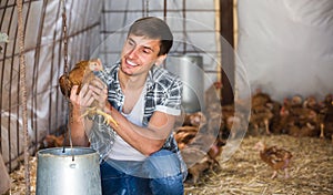 Smiling countryman holding brown chicken