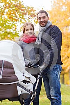 Smiling couple with baby pram in autumn park