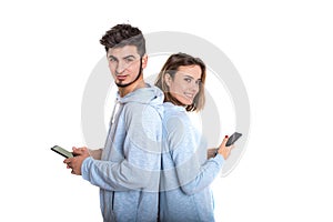 Smiling couple backwards with their mobile phones isolated on white