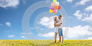 Smiling couple with balloons over sky and grass