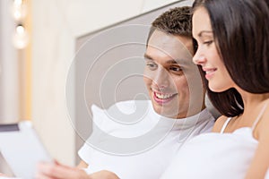 Smiling couple in bed with tablet pc computers