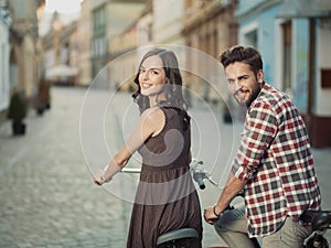 Smiling couple on bicycles in town