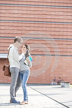 Smiling couple with books standing at university campus