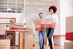 Smiling Couple Carrying Boxes Into New Home On Moving Day