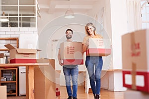 Smiling Couple Carrying Boxes Into New Home On Moving Day