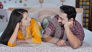 Smiling couple in casual clothes talking while laying down in bed - Young Indian couple, Newly married couple, Indian family