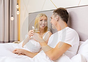 Smiling couple with champagne glasses in bed