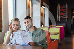 smiling couple choosing meal from menu
