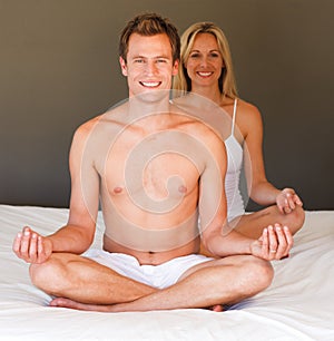 Smiling couple doing exercises on bed